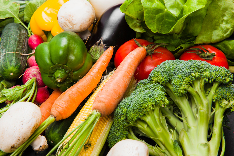 A colorful spread of seasonal vegetables, grains, legumes, and fresh ingredients arranged on a kitchen counter